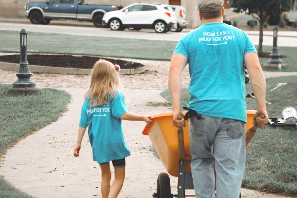 father-and-daughter-helping-push-wheel-barrel